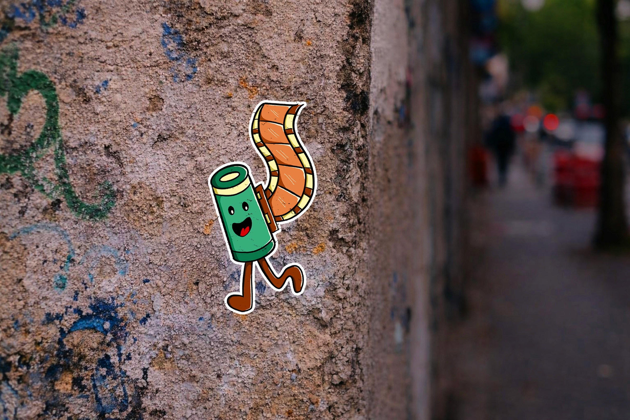 Smiling film-roll sticker on a textured concrete pole.