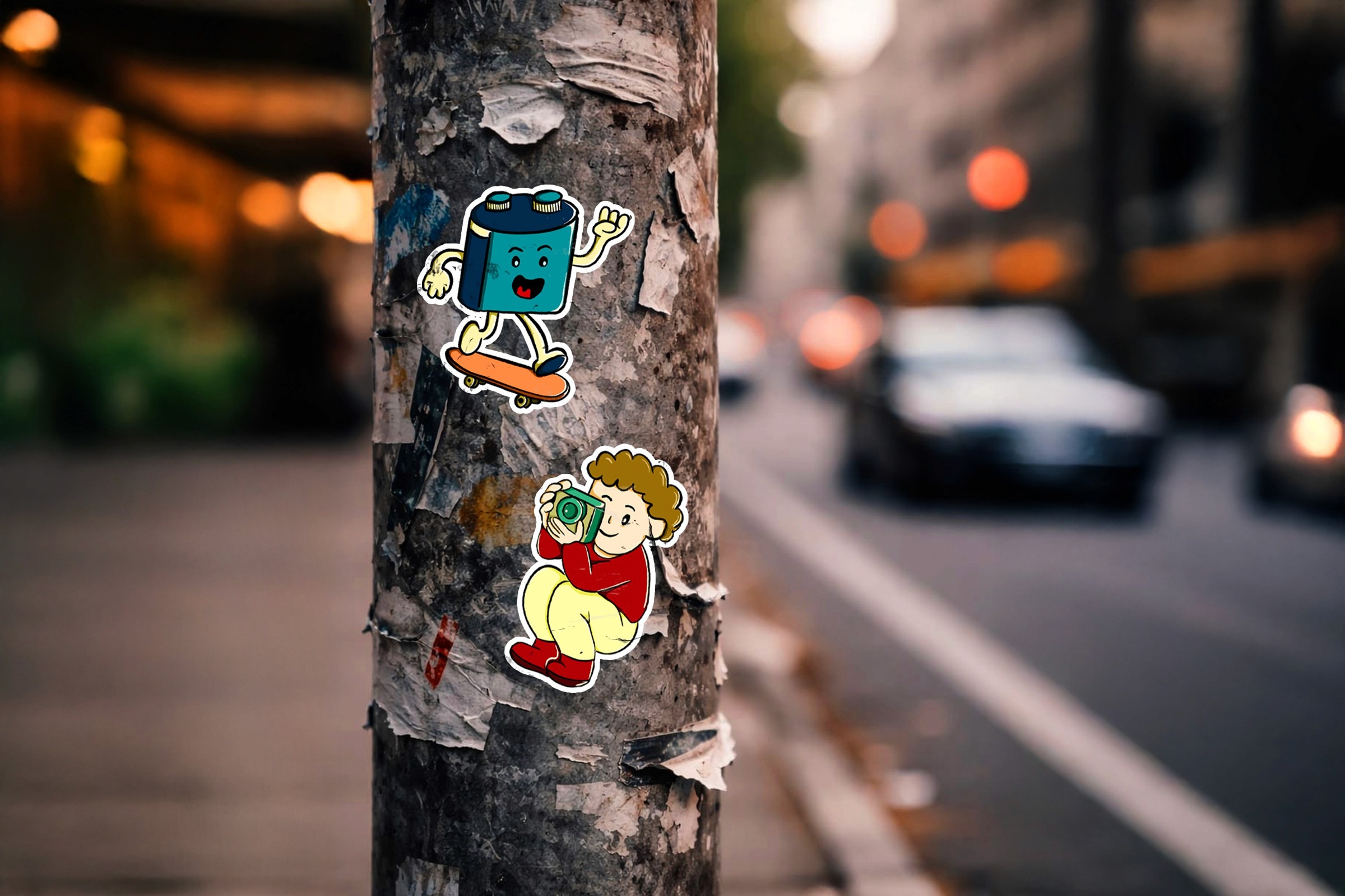 Camera and photographer character stickers applied to a street-side pole.