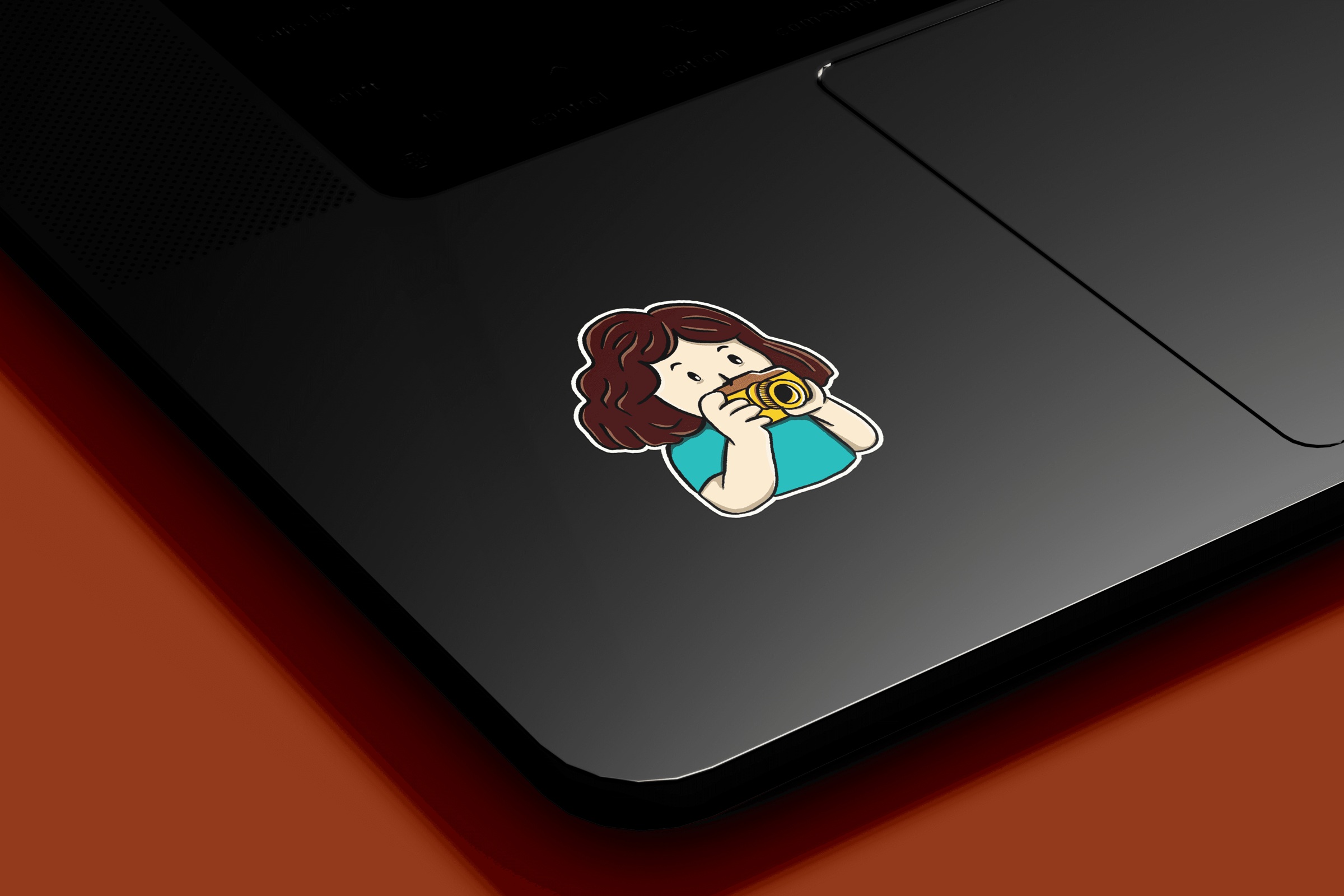 Photographer sticker on the corner of a dark laptop.